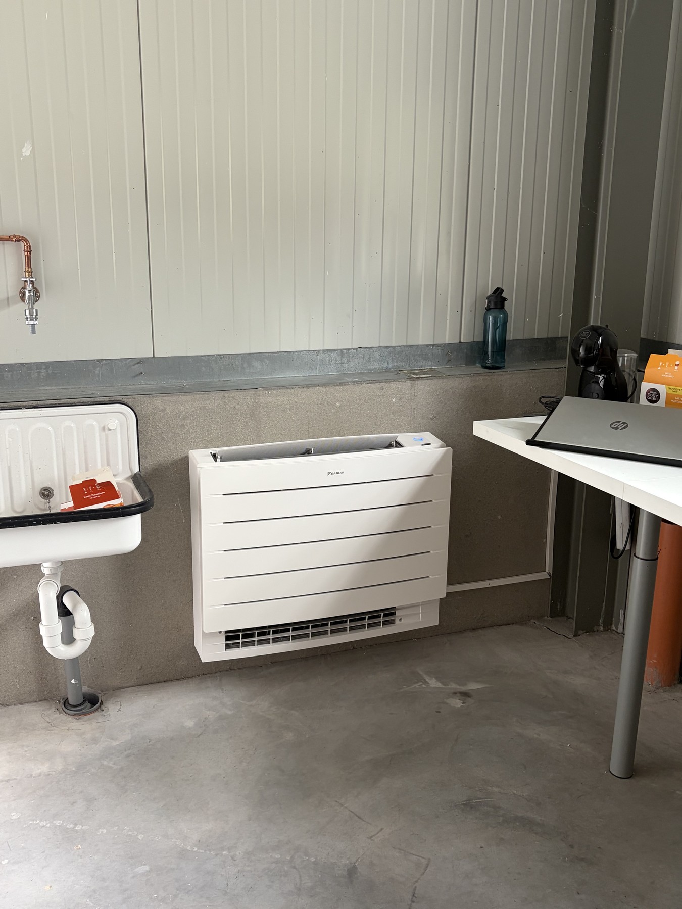 Daikin-vloermodel onder een wastafel in de kantoorruimte van een nieuwbouwmagazijn in Oostkamp
